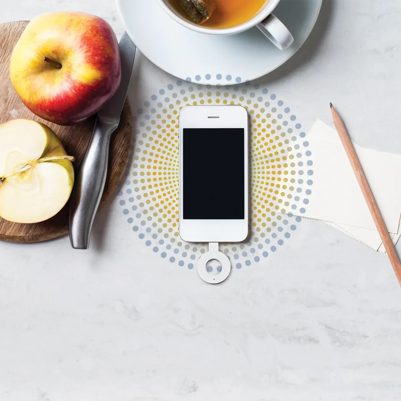 Paper records, cup of tea, a mobile phone and a pencil on a white office desktop.